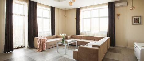 Una sala moderna con un sofá modular, una mesa de centro de vidrio e iluminación colgante.