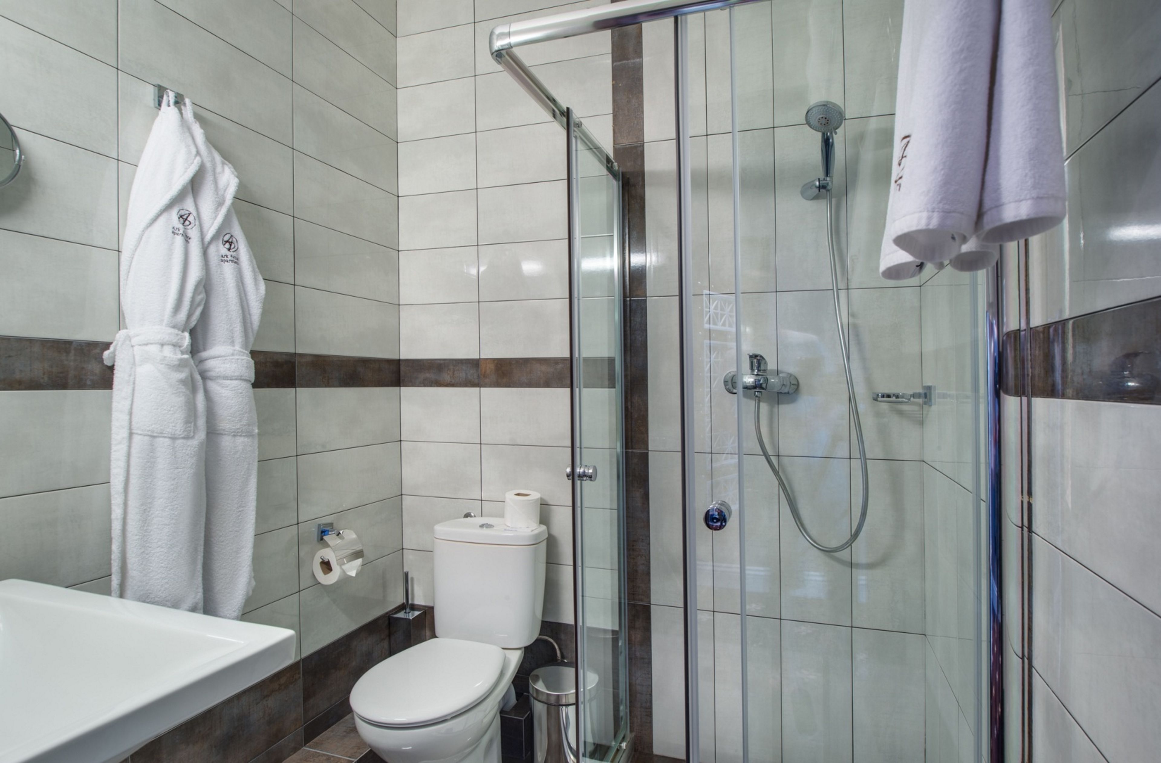 A modern bathroom with a glass-enclosed shower, a toilet, and a sink.