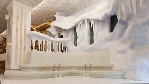 Un baño con techo y paredes de un diseño único que imita el hielo, con una zona central de lavamanos y múltiples grifos.