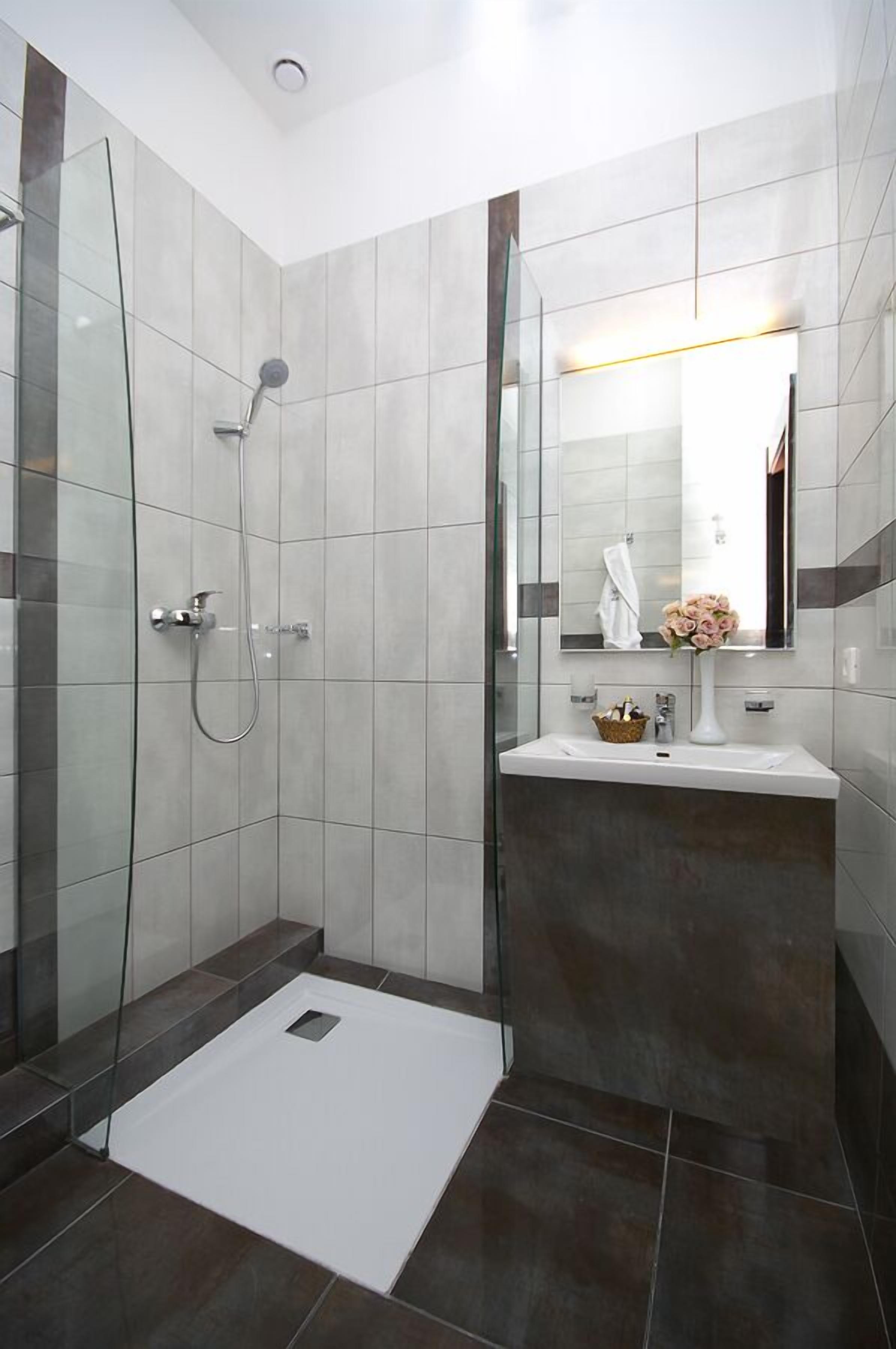 A modern bathroom with a glass shower enclosure, a white sink, and a mirror above it.
