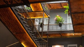 A multi-level interior with a staircase, potted plants, and a balcony with a view. - Hotel Principal (Mexico City)