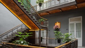 A multi-level interior with a staircase, metal railings, and potted plants. - Hotel Principal (Mexico City)