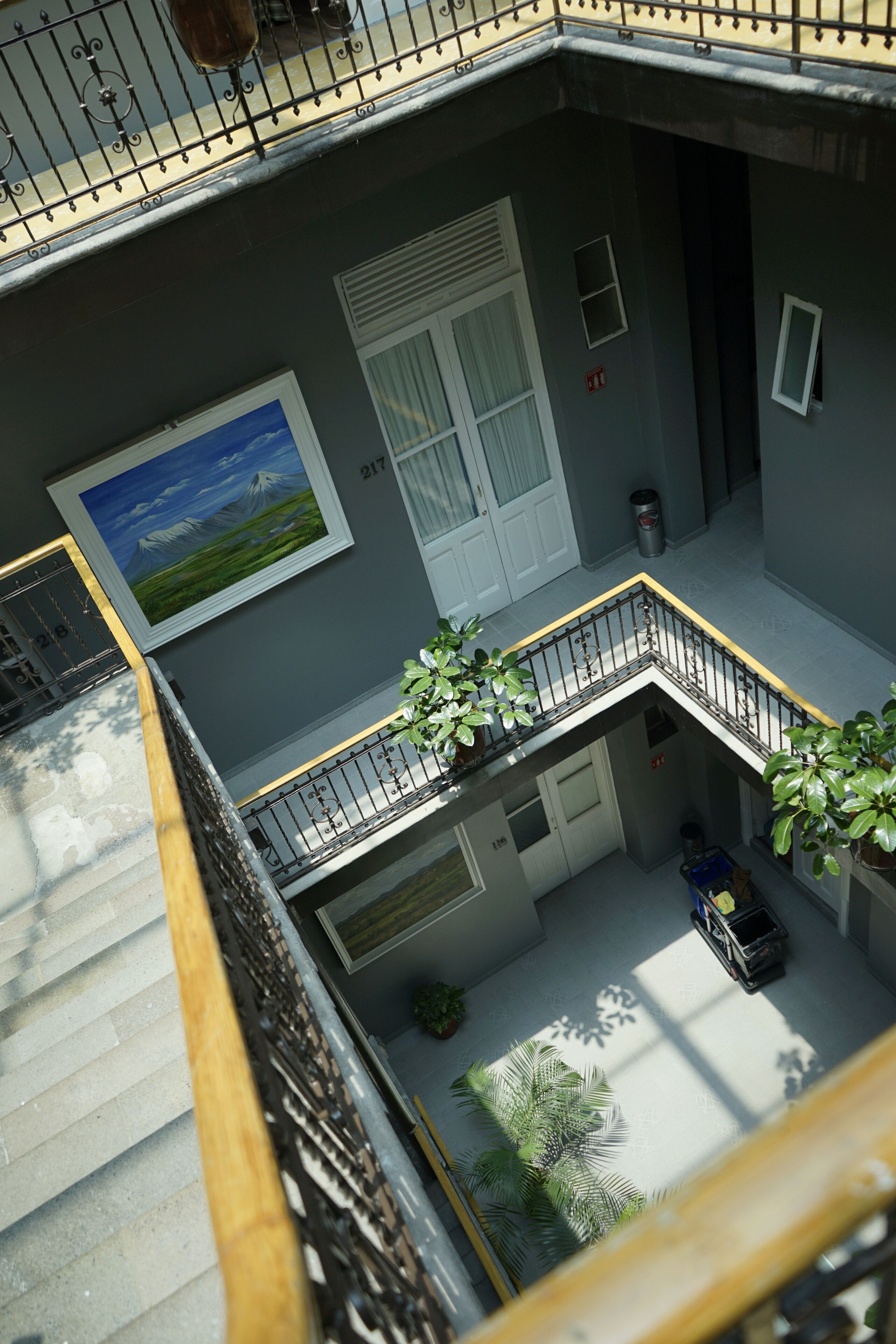 A multi-level residential building with a balcony, a white door, and a painting of a landscape.