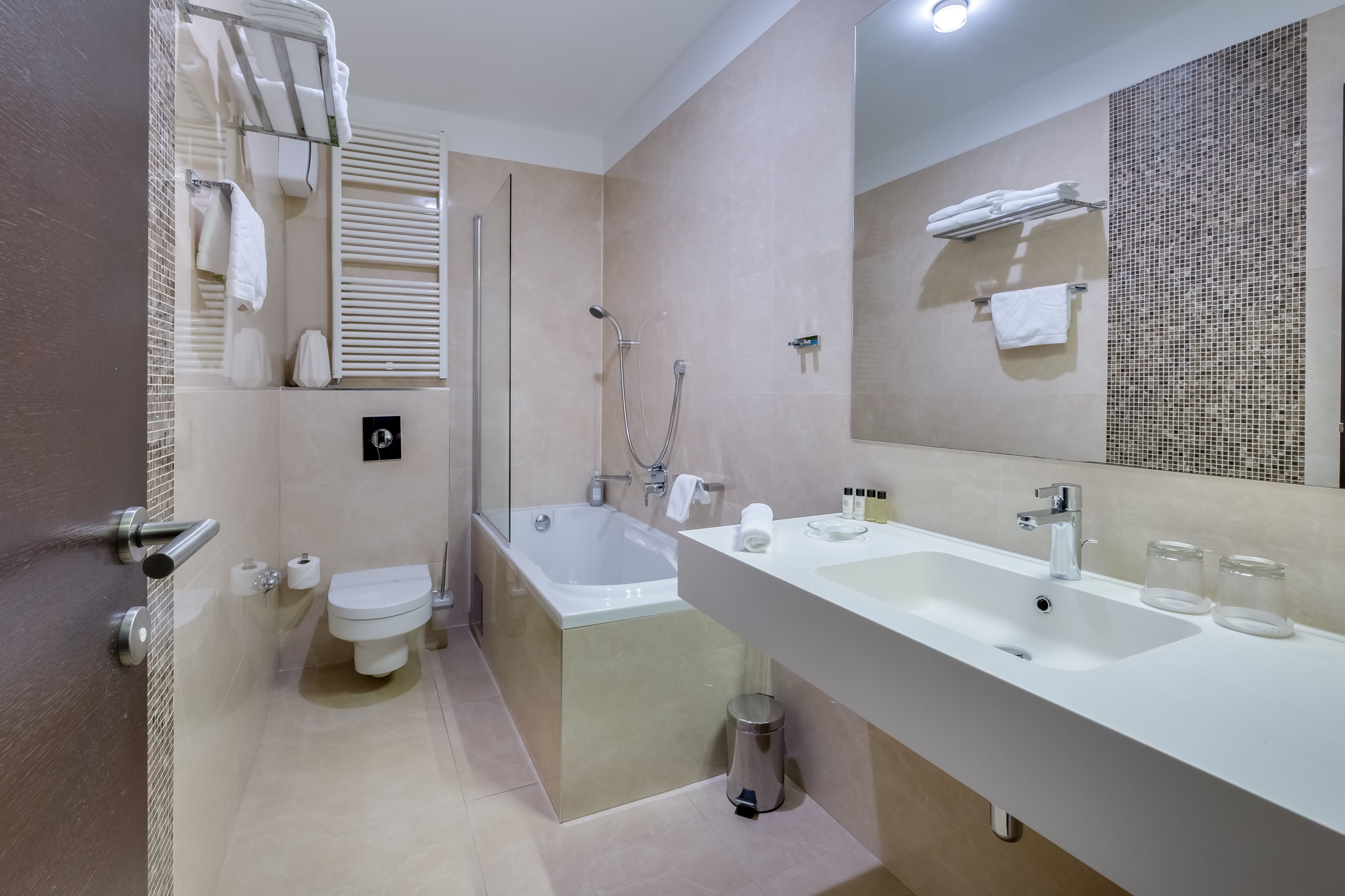 Un baño moderno con bañera, inodoro y un amplio tocador con espejo.