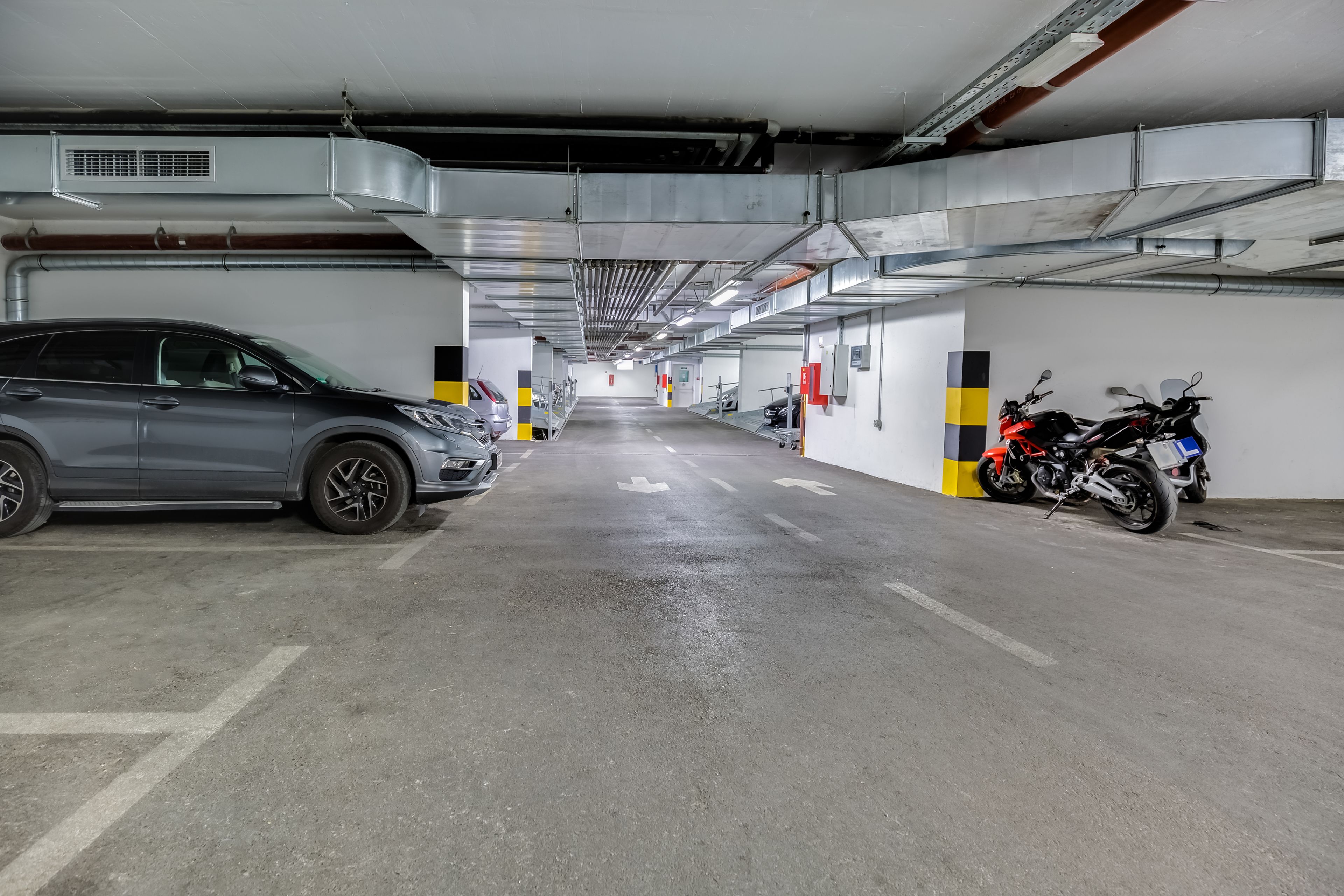 A multi-level parking garage with cars and motorcycles parked.