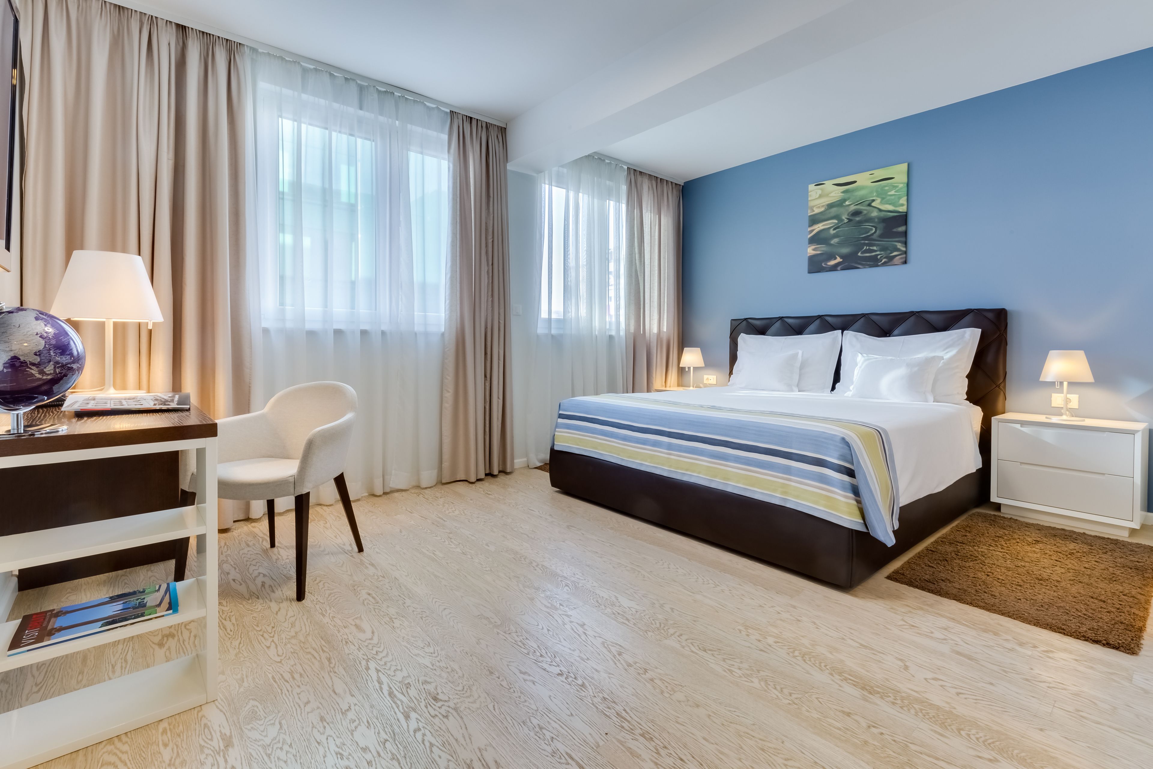A hotel room with a bed, a desk, a chair, and a globe on the desk.