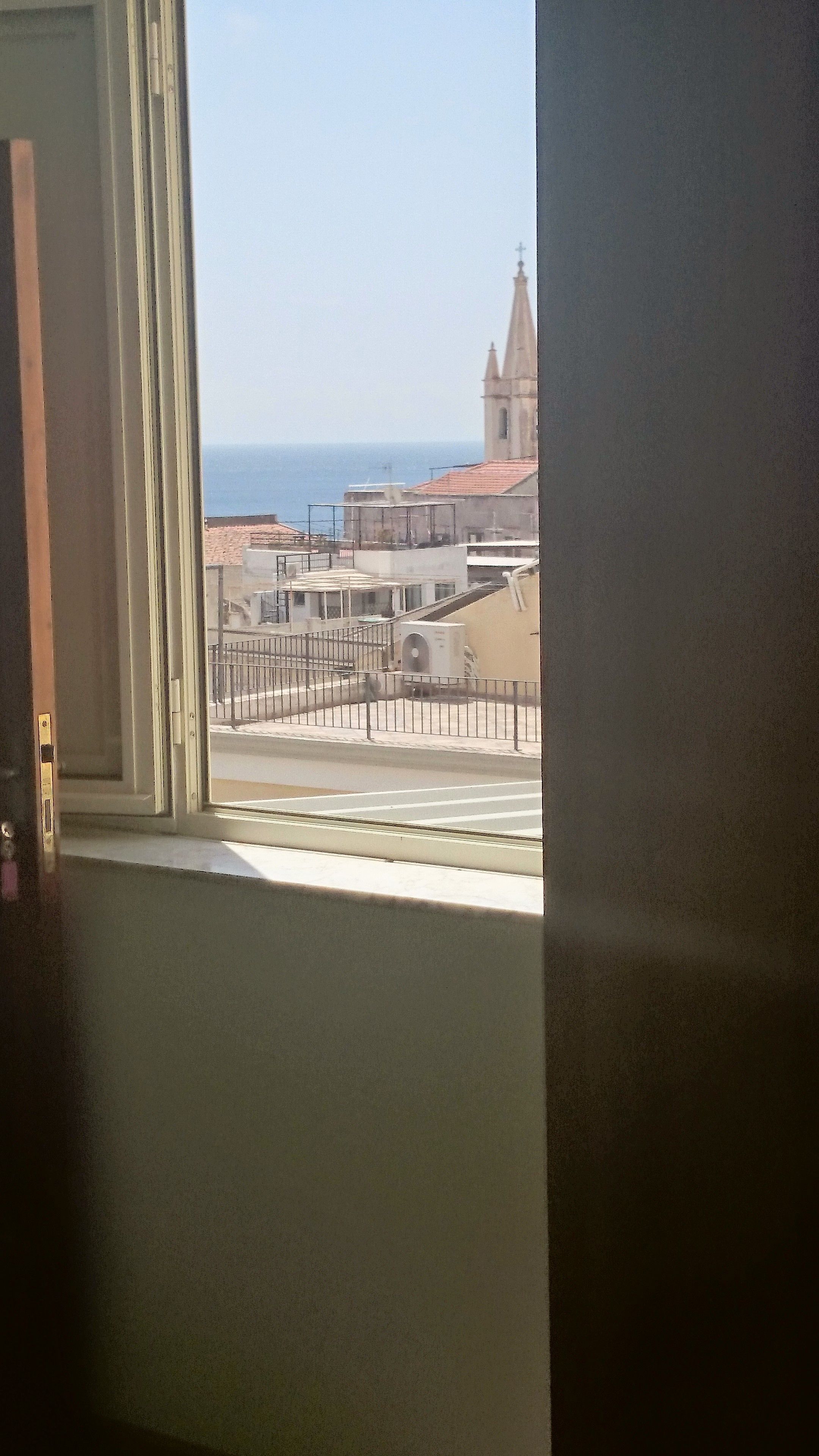 Une vue depuis une fenêtre donnant sur une zone côtière, avec des bâtiments et une église.