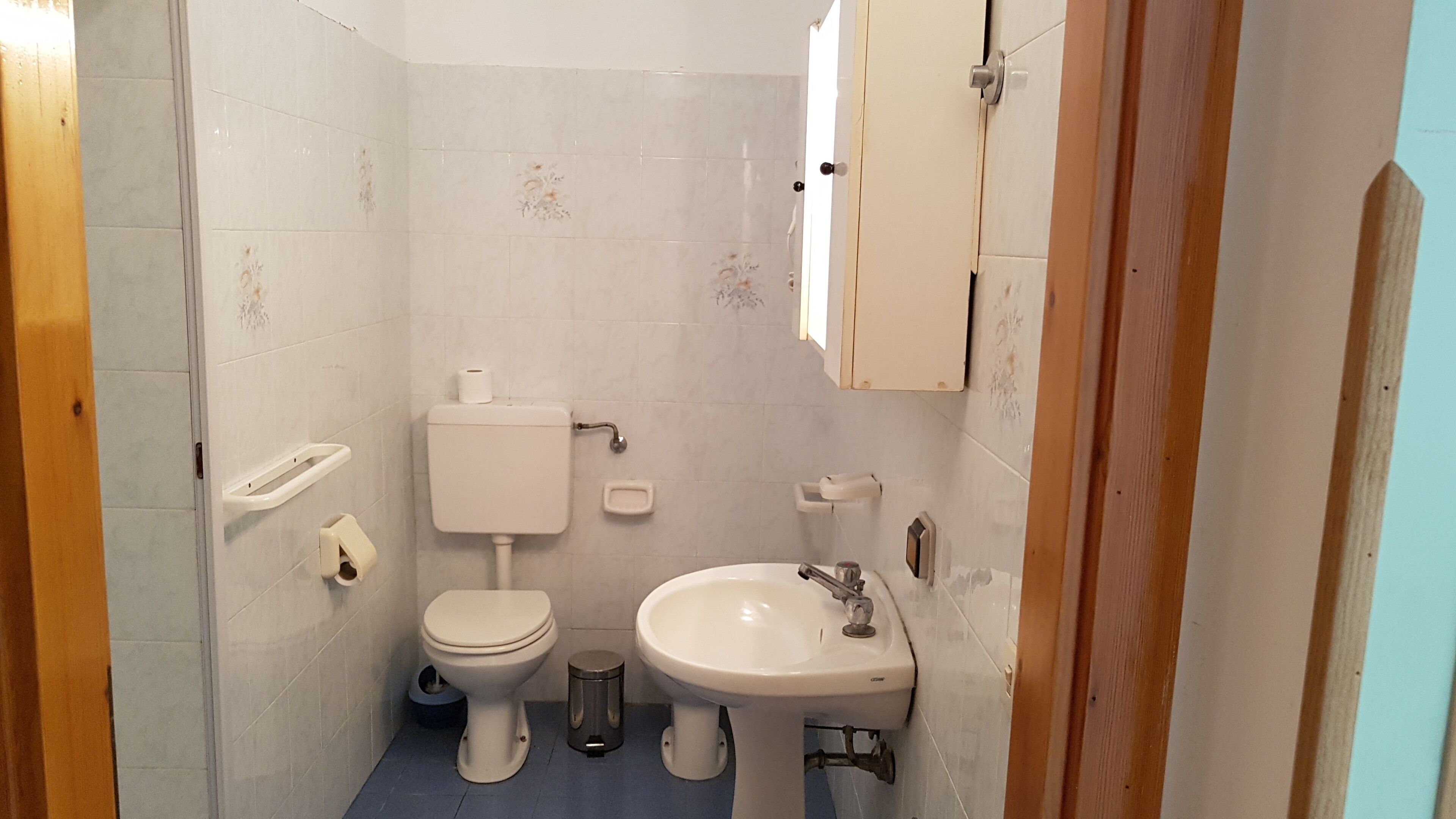 A small, compact bathroom with a toilet, sink, and a cabinet above the sink.