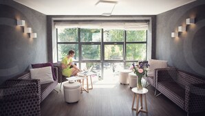 Une pièce moderne avec de grandes fenêtres, un canapé, une petite table et une chaise.