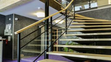 Un escalier avec des marches en bois et des rampes noires, menant à un niveau supérieur.