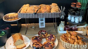 Une table de buffet proposant diverses viennoiseries, notamment du pain, des pâtisseries et une miche de pain.