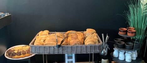 A buffet table with various baked goods, including bread, pastries, and a loaf of bread.