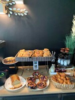 Une table de buffet proposant diverses viennoiseries, notamment du pain, des pâtisseries et une miche de pain.