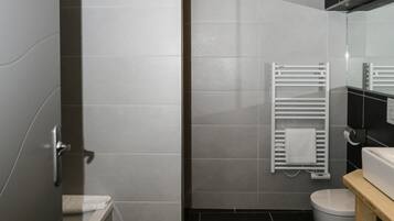 A modern bathroom with a bathtub, toilet, and a towel rack.