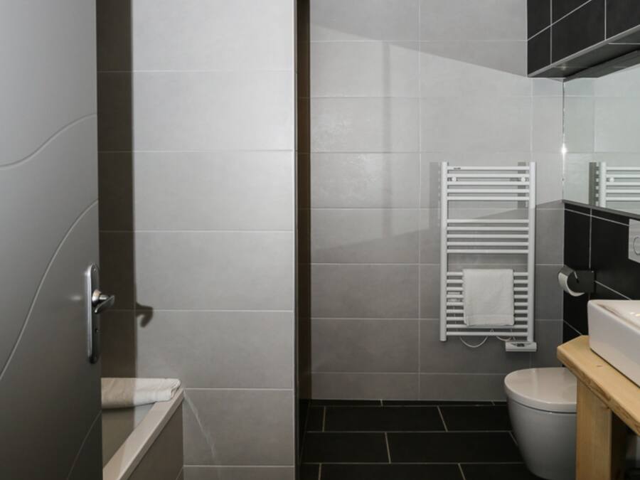 A modern bathroom with a bathtub, toilet, and a towel rack.