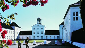 A large white building with a central tower, surrounded by smaller white buildings. - Benniksgaard Bed & Breakfast (Grasten)