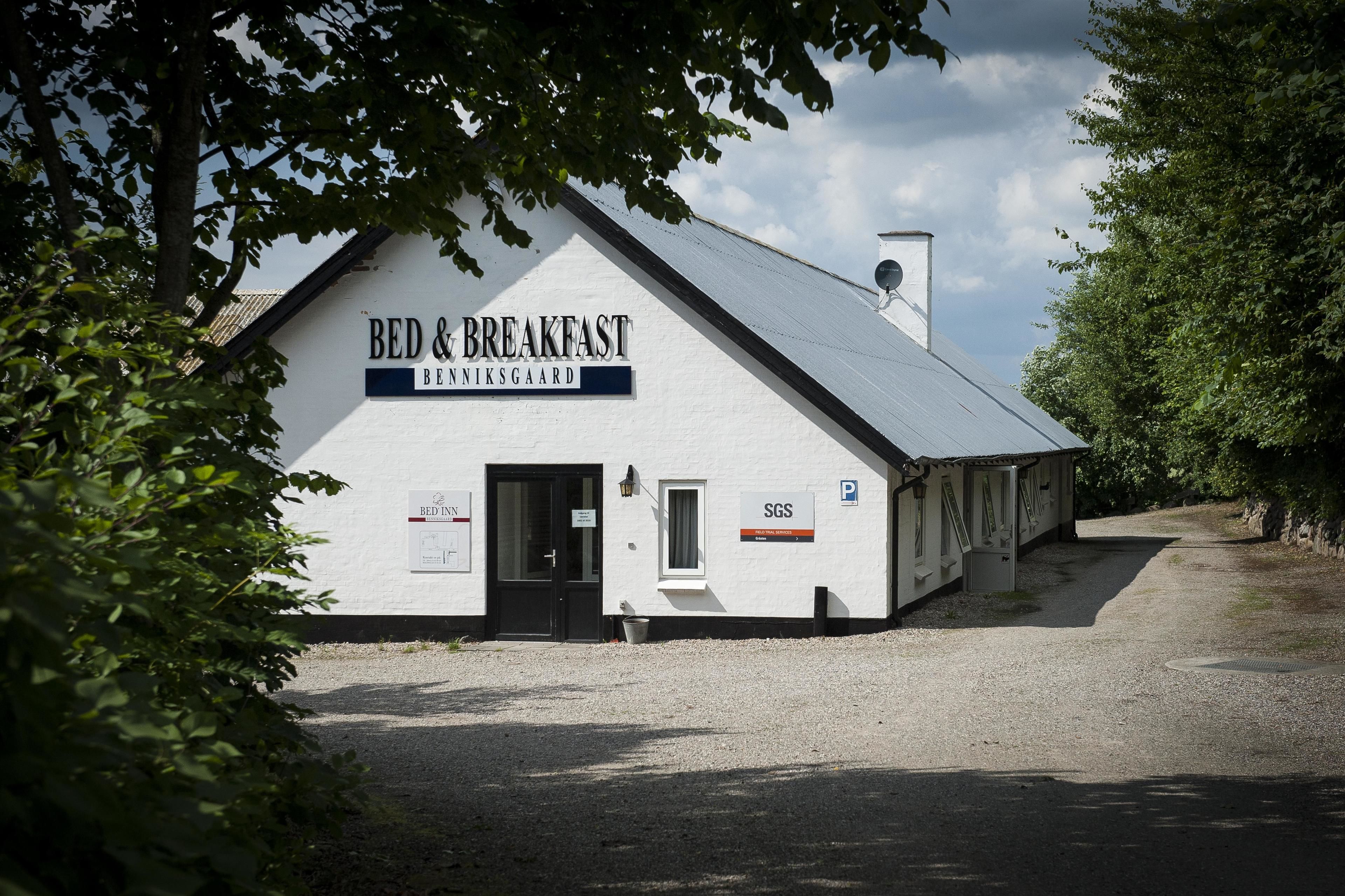 A white building labeled "BED & BREAKFAST" with a gravel driveway and a parking sign.