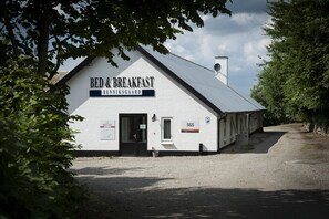A white building labeled "BED & BREAKFAST" with a gravel driveway and a parking sign.