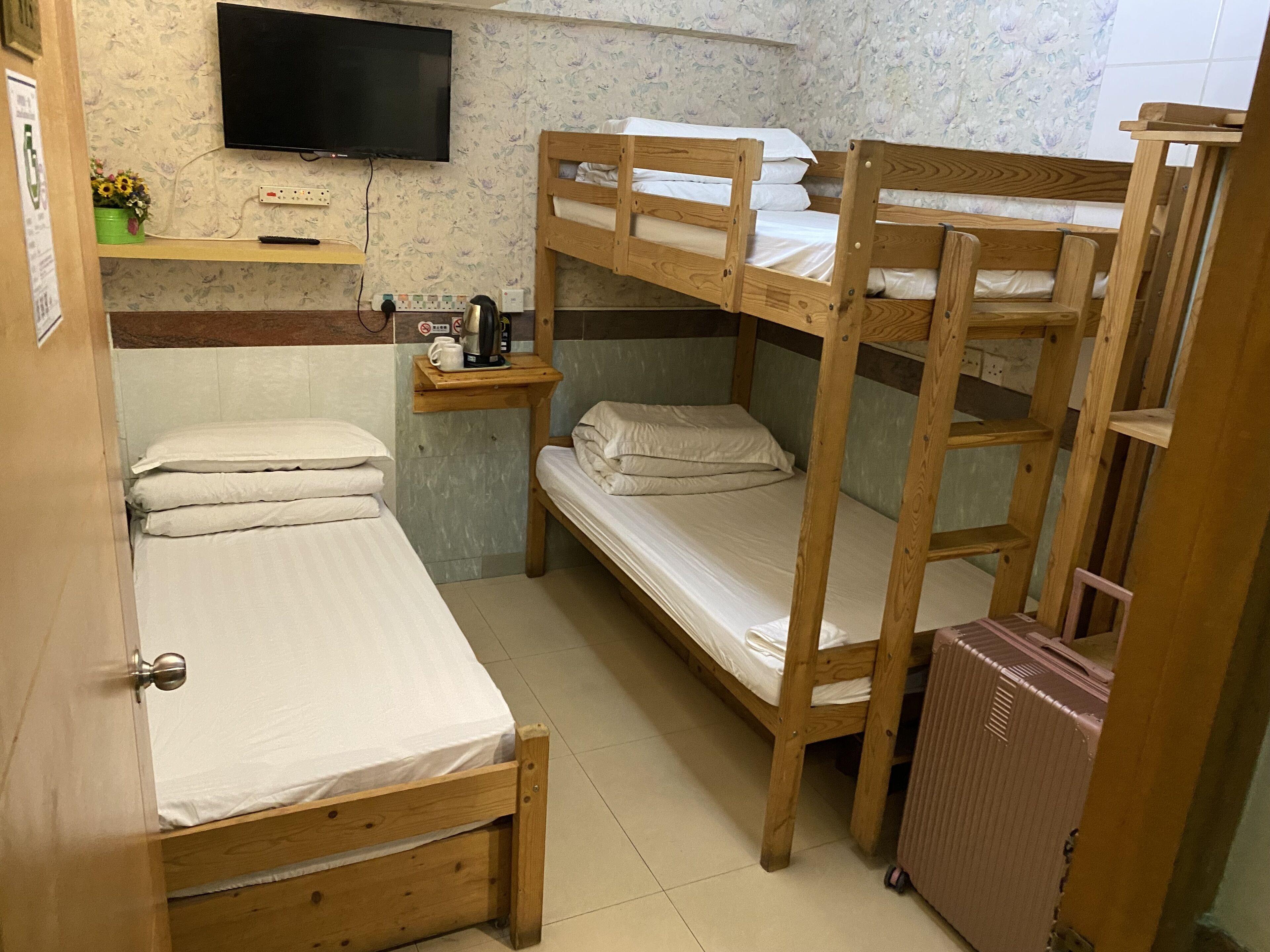 A dormitory room with bunk beds, a television, a coffee maker, and a small table.