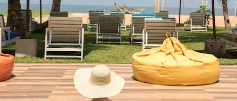 A poolside area with lounge chairs, a yellow bean bag, and a person relaxing in the water.