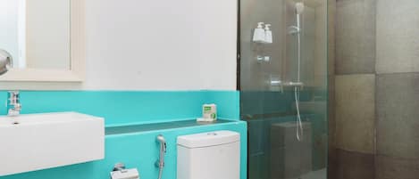 A modern bathroom with a glass-enclosed shower, a white toilet, and a turquoise vanity.
