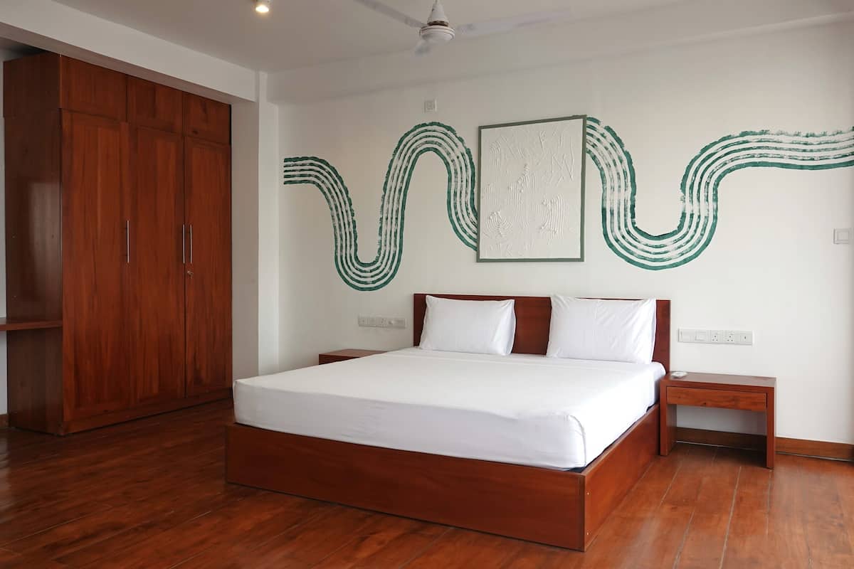 A bedroom with a wooden bed, a nightstand, a wardrobe, and abstract wall art.