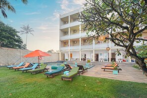 A hotel with a pool area, outdoor lounge chairs, and a multi-story building. - Hotel J Negombo (Negombo)