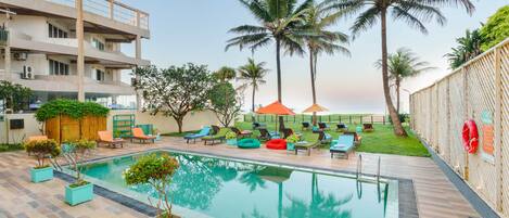 A swimming pool with lounge chairs and palm trees.
