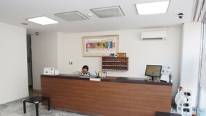 A reception desk with a computer monitor, a calendar, and a framed artwork on the wall. - Hotel Redent Ito (Ito)