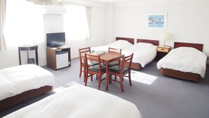 A hotel room with two single beds, a double bed, a desk with a television, a small refrigerator, a table with chairs, and a bedside lamp. - Hotel Redent Ito (Ito)