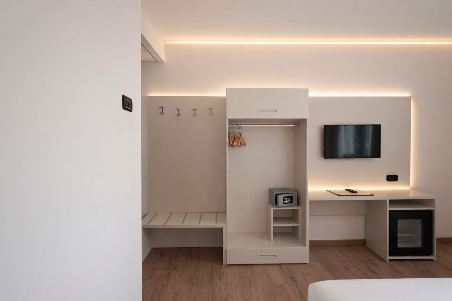 Un dormitorio moderno con armario empotrado, mesita de noche, televisor montado en la pared y un mueble bajo.