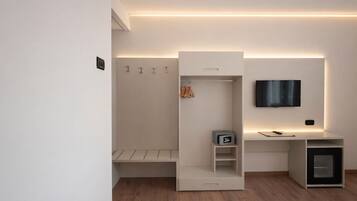 Un dormitorio moderno con armario empotrado, mesita de noche, televisor montado en la pared y un mueble bajo.