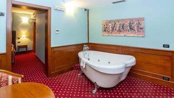 Un baño con bañera, paneles de madera, piso estampado rojo, un cuadro en la pared y una puerta que da a otra habitación.