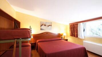 Camera d'albergo con letti a castello, una testiera in legno, un comodino con lampada e una finestra con tende.