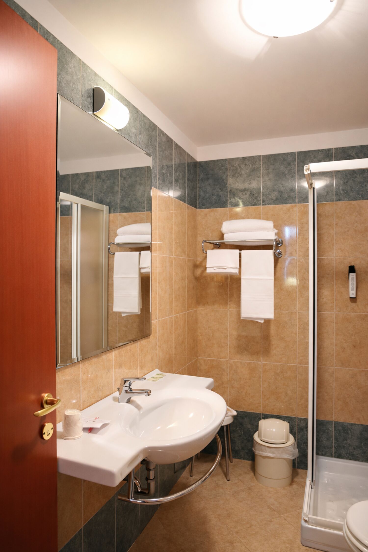 A bathroom with a sink, mirror, towel rack, and shower.