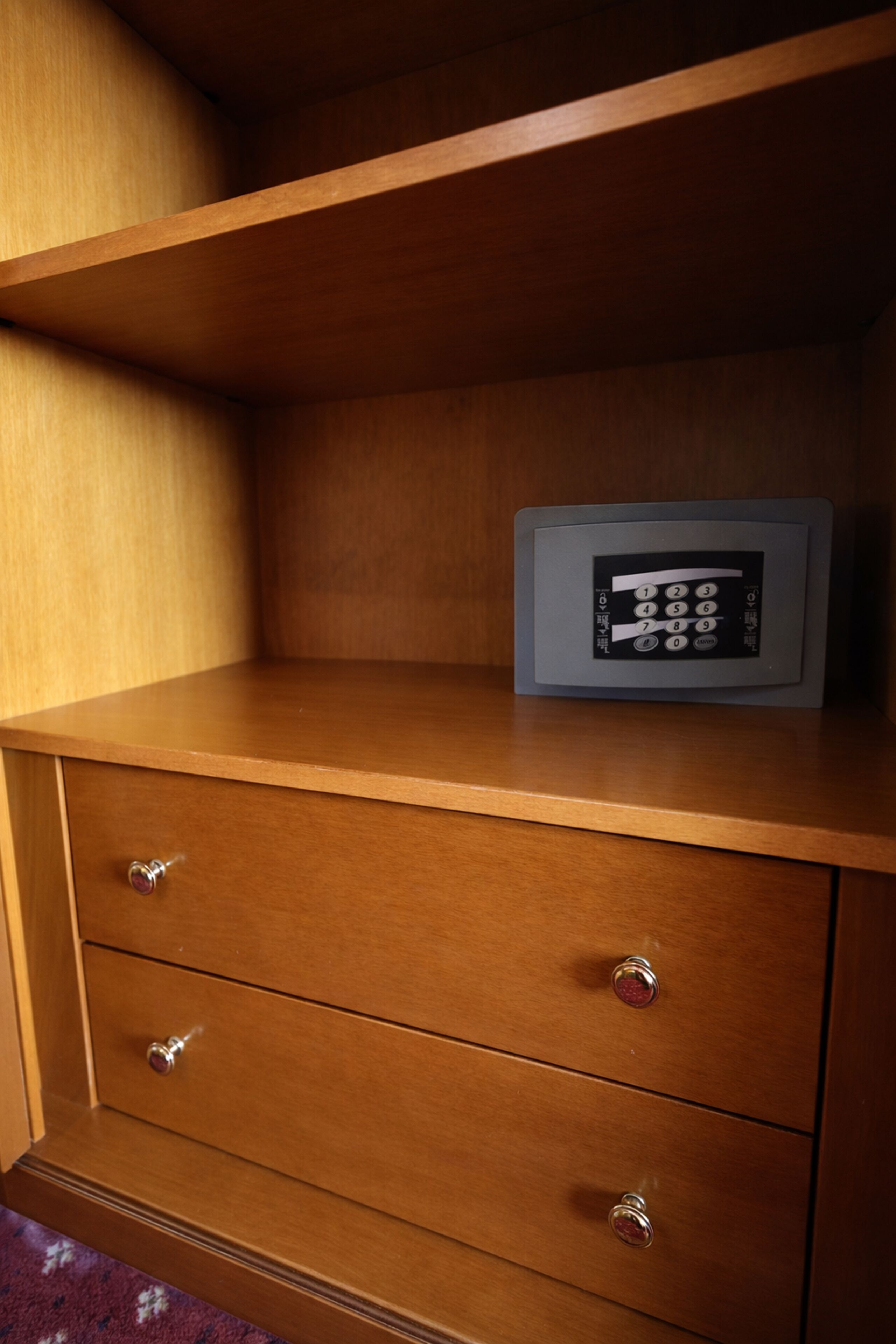 A wooden cabinet with a built-in safe containing a keypad.