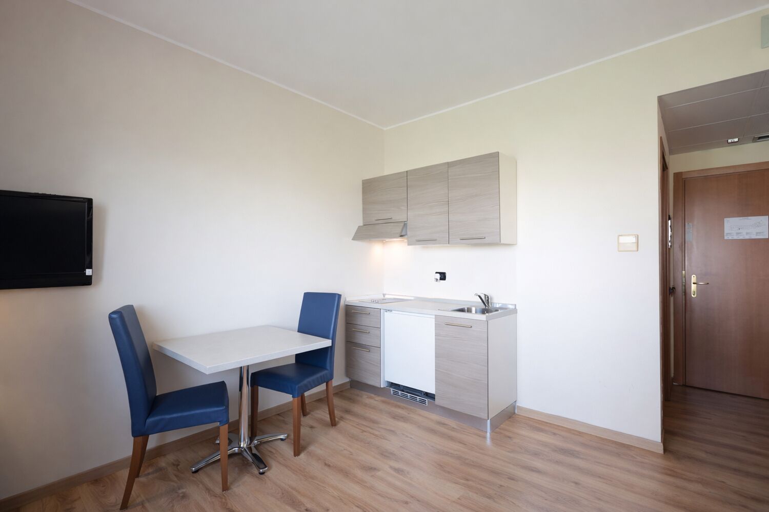 A compact kitchen with a dining table and chairs, a built-in oven, and a small window.