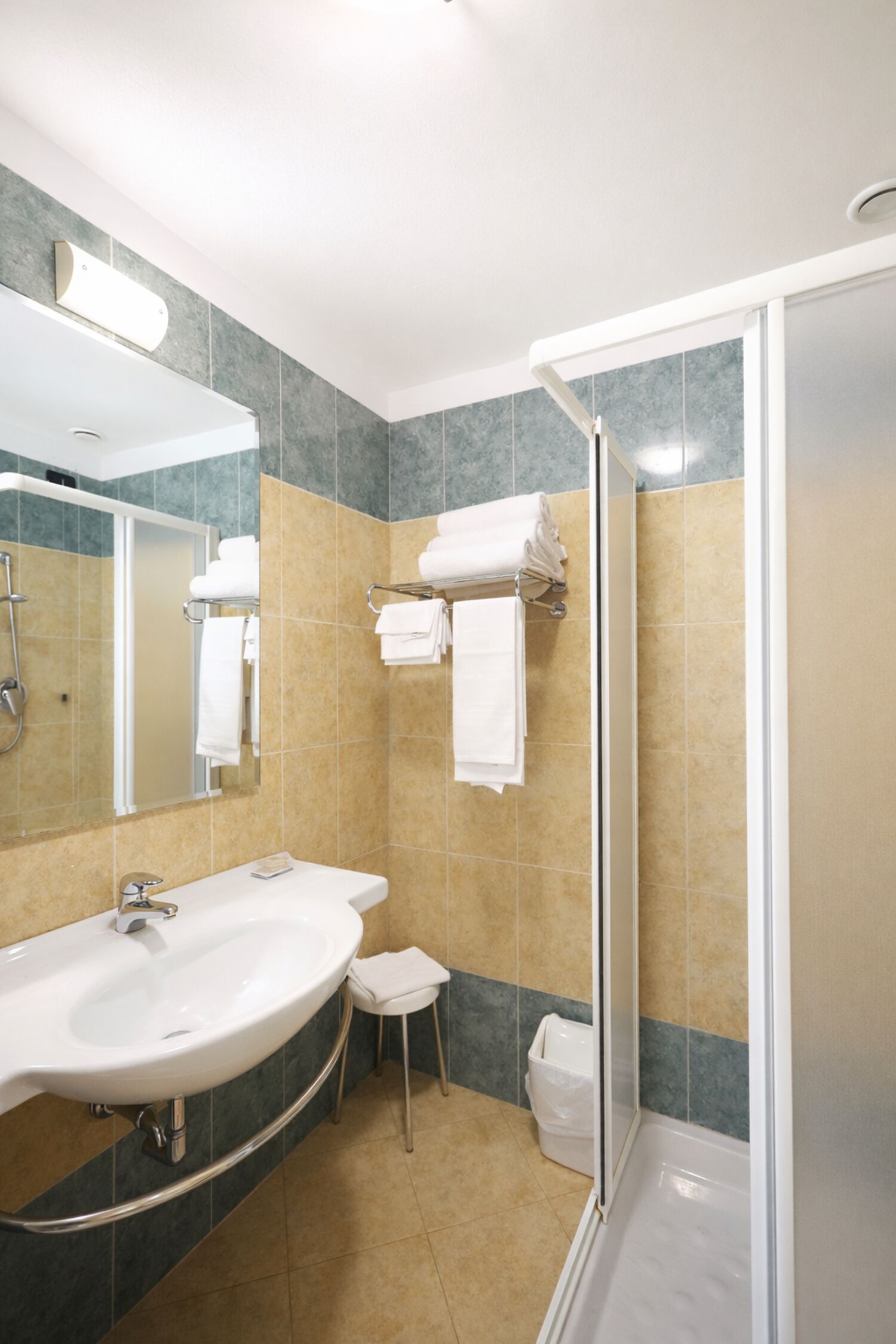 Une salle de bain équipée d’un lavabo, d’un miroir, d’une douche et d’un porte-serviettes.