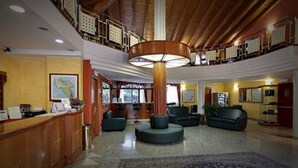 A spacious lobby with a high ceiling, a central column, and seating areas. - LVG Hotel Collection – Riz (San Genesio ed Uniti)