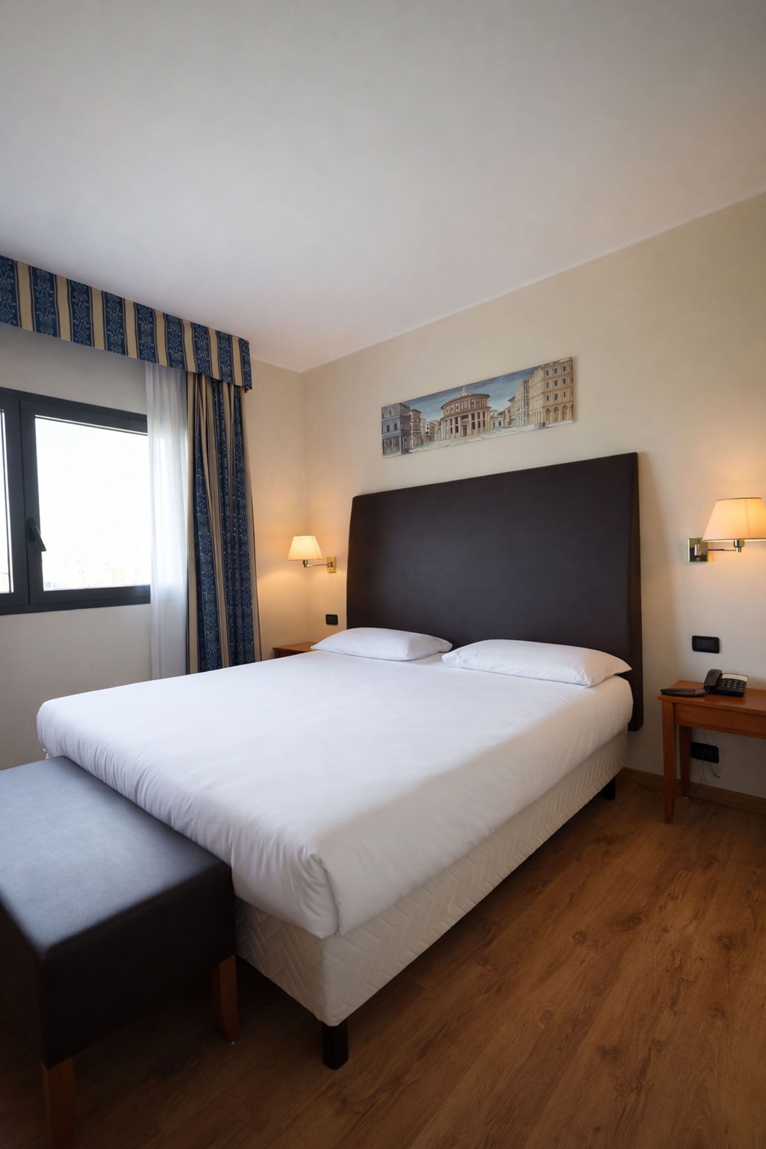 Habitación de hotel con una cama grande, una mesita de noche, una lámpara y un cuadro en la pared.