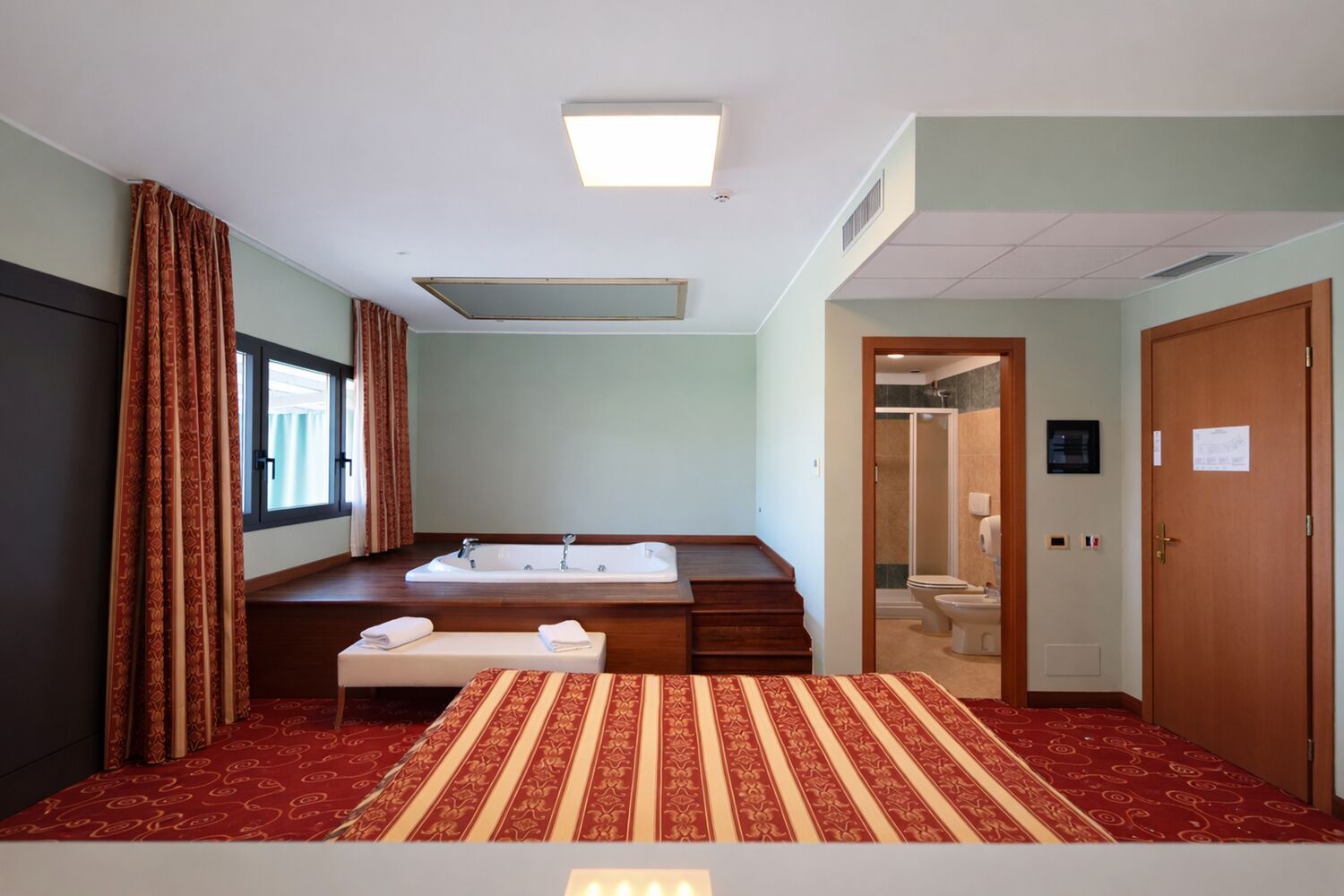 A hotel room with a large bed, a bathroom with a bathtub, and a shower.