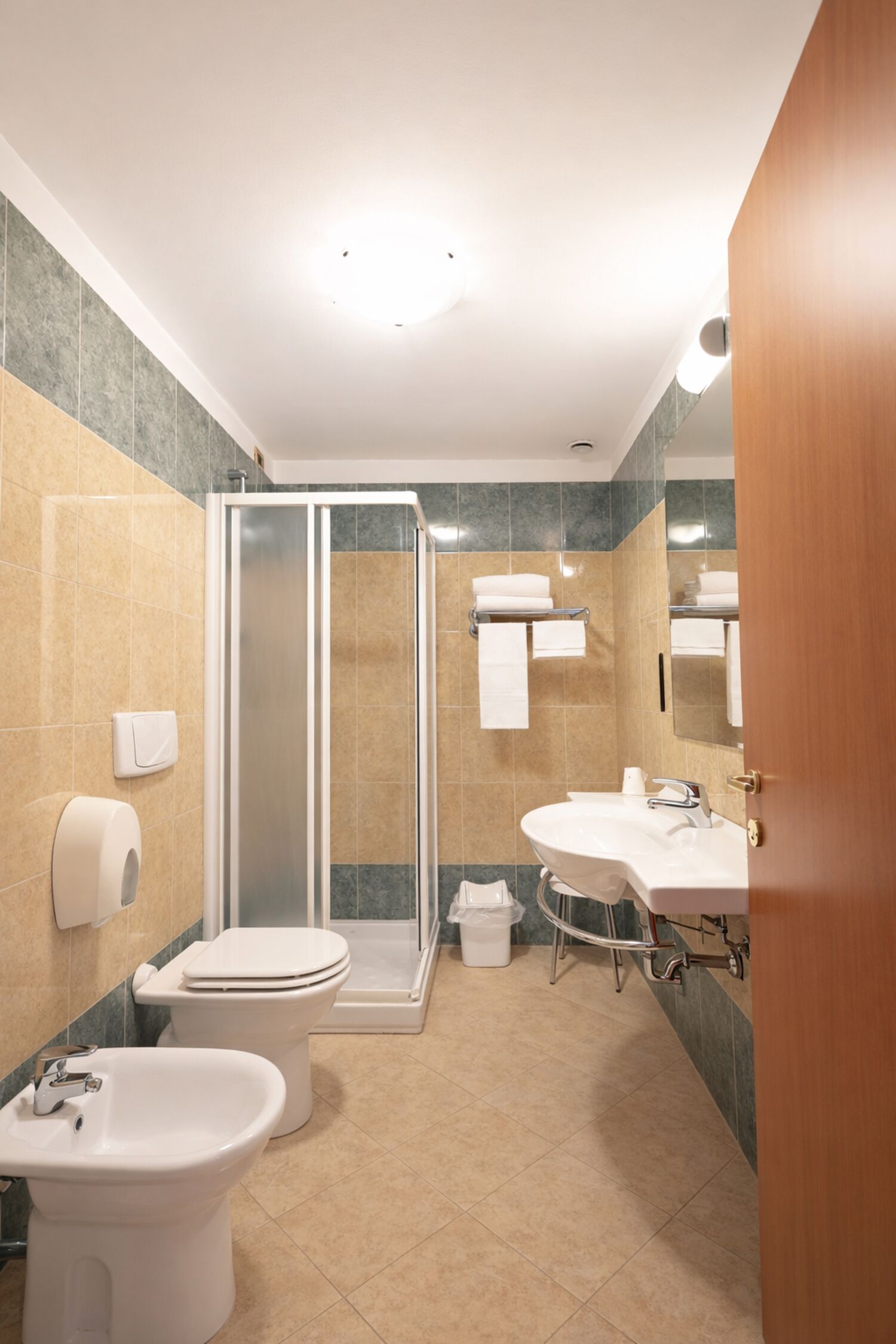 A modern bathroom with a toilet, bidet, sink, and shower.