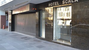 A hotel facade with a closed shutter, a visible number 34, and a sign reading "HOTEL SCALA". - Hotel Scala (Porto Alegre)
