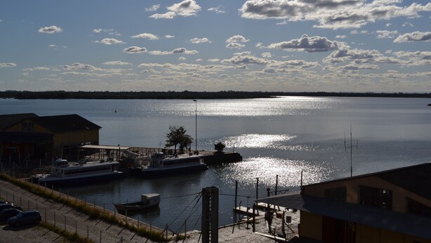 A marina with boats docked, a clear sky, and a calm body of water reflecting sunlight. - Hotel Scala (Porto Alegre)