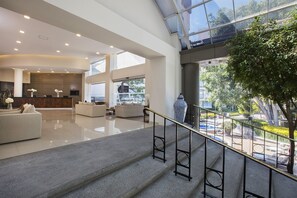A spacious lobby with a staircase, a reception desk, and a large window overlooking a garden. - Krystal Satélite María Bárbara (Tlalnepantla de Baz)