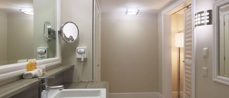 A bathroom with a sink, mirror, and towel rack.