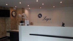A reception area with a clock, a potted orchid, and a sign that reads "HL Logos". - Logos (Warsaw)