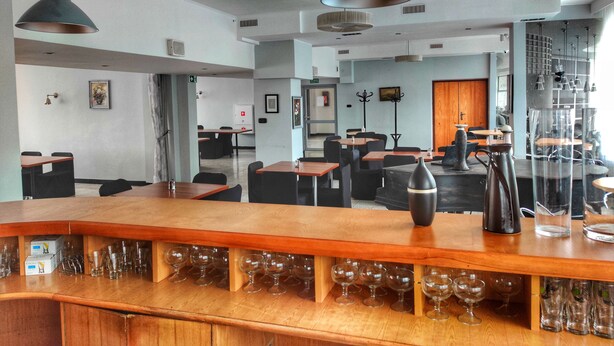 A modern bar area with wooden counters and multiple wine glasses. - Logos (Warsaw)
