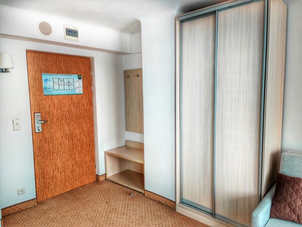Habitación de hotel con puerta de madera, un letrero azul, un espejo, una silla azul y una alfombra marrón.