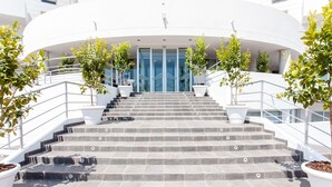 A set of stone steps leading to a modern building entrance with glass doors and white railings. - Scialì Hotel (Vieste)
